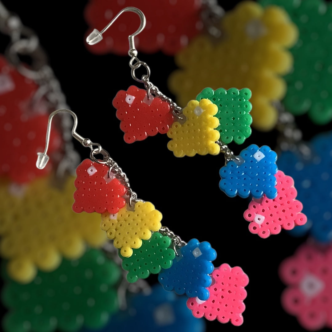 Handmade fuse bead earrings featuring long rainbow heart drop design with stacked pixel hearts and nickel-free hook findings on kraft card backing