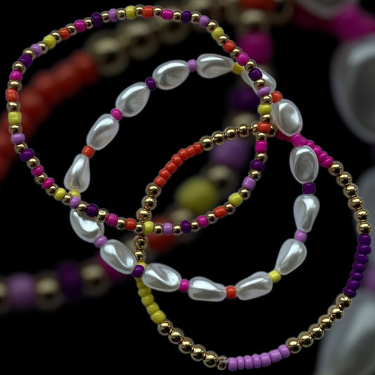 Electric Pearls bracelet stack – colourful beads with pearl drops and gold accents

3-piece handmade stretch bracelet set with pearl-look beads and vibrant colours

Festival-ready beaded bracelet stack – Electric Pearls by Pxl Nate

White pearl drop and gold bead bracelet trio with rainbow seed beads

Bold and shiny stretch bracelet set – handmade in the UK