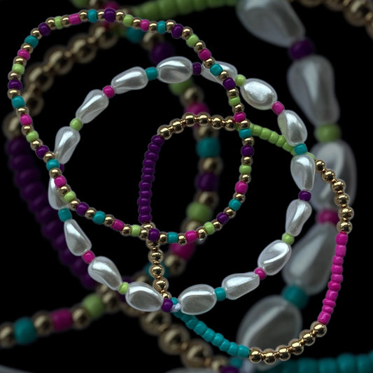 Tropic Pearl bracelet stack – pearl drop beads with teal, pink, and purple

Bright handmade bracelet trio with gold and tropical seed beads

Tropical-inspired beaded bracelet stack – Tropic Pearl by Pxl Nate

3-piece bracelet set with pearl-look beads and vibrant tones

Handmade stretch bracelet set with gold accents – UK made

